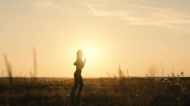 Sağlıklı koşu ve açık hava egzersiz konsepti. Güneşte koşu antrenmanı. Yazın genç bir kadın gün batımında parkta koşar. Şafakta spor için gidiyor. Güneşin peşinden koş. Sonbahar eğitimi