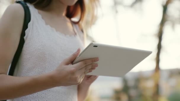 Şehir caddesinde dijital tablet baskı mesajları kullanan bir iş kadını. Öğrencilerin elleri tabletin ekranına dokunuyor. Tabletle çalışan serbest çalışan kadın kaldırımda yürüyor.. — Stok video