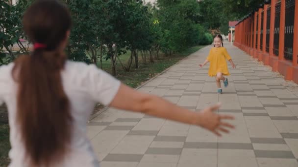 Happy Child, córka biegnie do mamy, przytula ją latem w parku na ulicy. Szczęśliwa rodzina. Beztroskie dzieciństwo, radosny bieg dziecka do matki. Dziecko radośnie bawi się latem na ulicy z rodzicem — Wideo stockowe