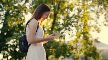 Kentte kaldırımda yürüyen tabletle çalışan serbest çalışan bir kadın. Şehir caddesinde dijital tablet baskı mesajları kullanan bir iş kadını. Öğrencilerin elleri tabletin ekranına dokunuyor.