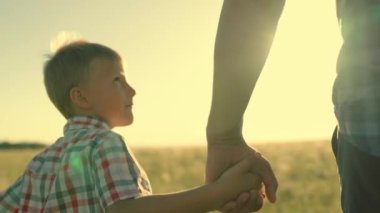 Oğlu, babası, annesi güneşin altında parkta el ele yürür. Parktaki insanlar. Mutlu aile yürüyüşleri, dışarıda baba oğul. Mutlu aile çocukluk hayali kavramı. Ebeveynler, çocuklar. Oğul baba birlikte anne