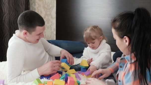 Pappa, mamma, dottern leker med kuber på dagis i sängen. Lära barn genom lek. Barn, far och mor leker familjehem. En lycklig familj. Pedagogiska spel för barn. — Stockvideo