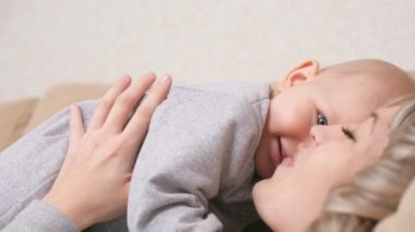 Komik küçük çocuk annesiyle kollarında oynuyor. Mutlu bir aile. Bebek ve anne birlikte oynar, sevinir, gülümser ve uçak gibi uçar. Genç anne kızıyla oynayan sevimli bir çocuk yetiştiriyor.