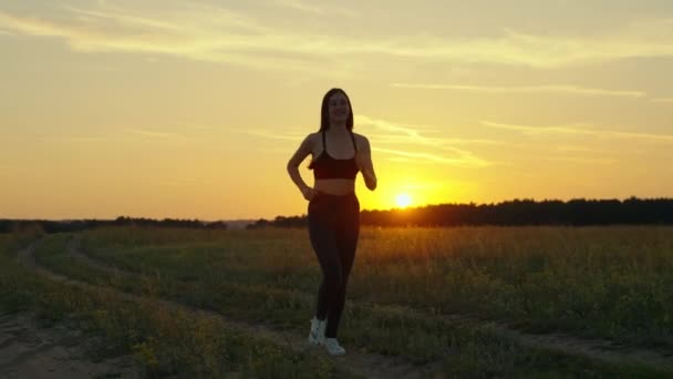 Trening joggingu. Wolna młoda kobieta lata w parku o świcie słucha muzyki ze słuchawkami. Zdrowy jogging i ćwiczenia na świeżym powietrzu koncepcja. Sport bieganie dla utraty wagi i promocji zdrowia — Wideo stockowe