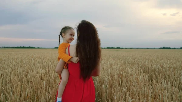 En liten dotter på bondmoderns klippor. Barnet och mamman reser på ett vetefält. Trevlig familjesemester. Barnet och föräldern leker i naturen. Lycklig familj på semester. — Stockfoto