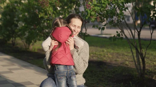 Barn, dotter springer till mamma och kramar henne i parken på gatan på våren. Lycklig familj. En bekymmerslös barndom, en glädjefylld bebis till mor. Små barn leker glatt på sommaren på gatan med föräldern — Stockfoto