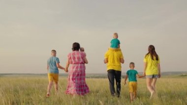 Sahada çocuklarla mutlu aile yürüyüşleri. Parktaki insanlar. Baba, anne, oğul, kız, parkta el ele tutuşuyorlar. Mutlu aile hayatı çocuklar. Ebeveynler, neşeli çocuklar yazın dinlenir. Aile tatili