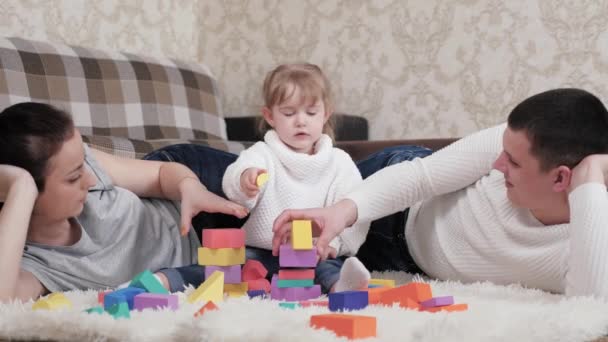 Papa mère, enfant jouer cubes dans la pépinière sur le sol. Enseigner l'enfant par des activités ludiques. Fille, père et mère jouent à construire une maison familiale. Bonne famille. Jeux éducatifs pour les enfants. — Video