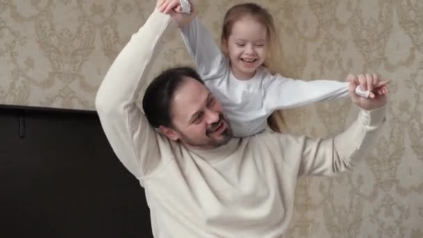 Daughter and young dad play together, raise their hands like an airplane at home, dream of flying.Happy family. Child, girl, plays, laughs and flies in an airplane in her fathers arms. Family game — Stock Video