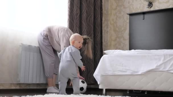 Mère et petit enfant, fils jouent au football dans la chambre, avec le ballon de football. Développez votre enfant grâce à des jeux sportifs actifs. Joyeux, sain, famille athlétique. Tout-petit, bébé, aime jouer avec maman à la maison. — Video