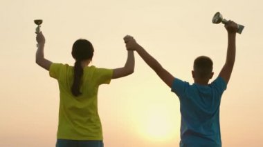 Gençler takım yarışmasını kazandı. Takım zaferini kutluyorlar. Kazananlar ellerinde fincanlarla seviniyor ve zıplıyorlar. Silüet mutlu sporcular spor erkek ve kadın takım çalışması şampiyonu. Yavaş çekim