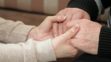 Genç bir kadın, kız, torun yaşlı bir baba, büyükbaba, erkek eli. İki nesildir genç bir kadın yaşlı bir adamın elini tutuyor. Aşk bakımı, yaşlı ebeveynlere yardım