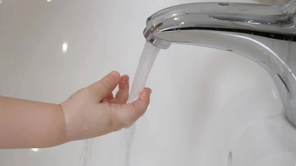 El niño se lava las manos con su madre en el baño sobre el lavabo. La madre ayuda a su hijo, hijo e hija a lavarse las manos en casa. Cariño, aprende a lavarse las manos solo. Una familia feliz. Higiene —  Fotos de Stock