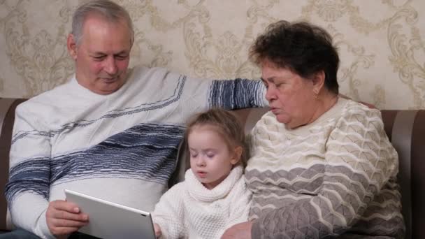 Padres y niños pequeños enseñando a sus hijos en línea usando tabletas digitales. Los abuelos modernos están jugando con el niño, chica en casa con la tableta digital. Una familia feliz. Pareja mayor con su nieta. — Vídeos de Stock