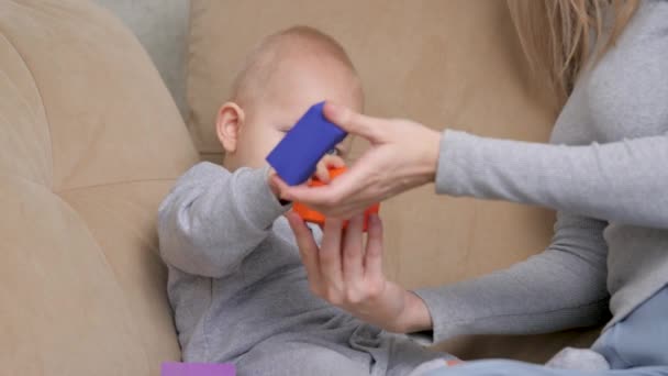 Educatieve spelletjes voor kinderen. Mam en baby spelen samen kindertjes kleurrijke blokjes op de bank in de kamer. Een gelukkig gezin. De moeder ontwikkelt motoriek bij het kind. Het onderwijzen van kind door spel — Stockvideo