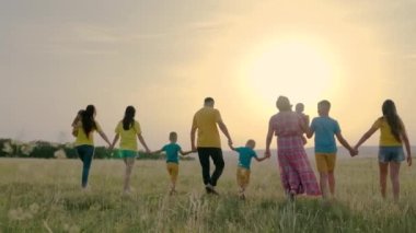 Sahada çocuklarla birlikte mutlu büyük bir aile yürüyüşü. Parktaki insanlar. Baba, oğlu olan bir anne, parkta el ele yürüyen bir kız. Mutlu çocuklar. Ebeveynler ve neşeli çocuklar yazın dinlenirler. Aile tatili