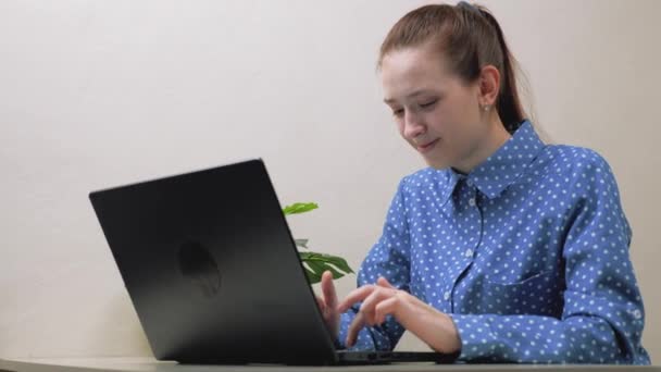 Egy lány tanul a számítógépénél az asztalnál a szobában. Szabadúszó fiatal nő a modern laptopon. Egy üzletasszony sms-t ír a laptop billentyűzetén. A számítógépen dolgozó üzletasszony női kezei. — Stock videók