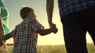 Oğlu baba, annesi güneşin altında parkta el ele yürür. Parktaki insanlar. Mutlu aile yürüyüşleri, erkek baba açık havada anne. Mutlu aile, çocukluk. Ebeveynler, çocuklar. Oğlu baba anne