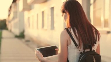 Öğrenci kız şehir caddesinde yürüyor, elleriyle tablete dokunuyor. Kentte tablet bilgisayarla çalışan serbest çalışan biri. İş kadını dışarıda dijital tabletle çalışıyor.