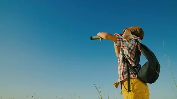 Bambino bambino bambino felice che gioca in parco in un casco aviatori guarda attraverso cannocchiale in estate sulla natura. Bambino figlio di sogni viaggiatore, fantasie contro il cielo blu sul parco giochi. Leader vincitore, viaggi. — Foto Stock