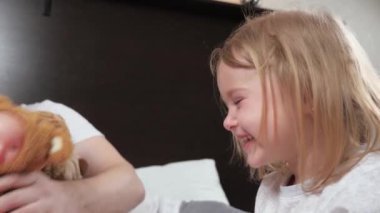 Mutlu çocuk evde babasıyla kanepede gülüp oynuyor. Baba kızıyla en sevdiği oyuncağıyla oynar, bebek güler ve eğlenir. Evde mutlu bir aile. Evde eğitim