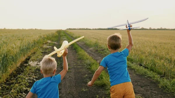 Çocuklar, çocuklar parkta buğday tarlasında ellerinde oyuncak uçakla koşuyorlar, uçmayı hayal ediyorlar. Çocuk oyuncağıyla uçakla oynuyor. Çocuklar koşar, rüya görür, takım çalışması yapar, seyahat eder. Mutlu aile tatilleri. — Stok fotoğraf