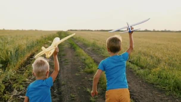 Chlapci, děti běží v parku přes pšeničné pole hrát s letadýlkem v ruce, sen o létání. Dítě si hraje se svou hračkou s letadlem. Děti utíkají, sní, týmová práce, cestování. Šťastný rodinný den. — Stock video