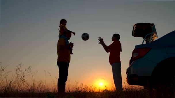 Papà con bambino, figlia sulle spalle, mamma, bambini giocano con la palla davanti al bellissimo tramonto. La famiglia felice viaggia in auto. Genitori e bambini si sono fermati in campeggio in auto. Viaggiare in auto — Video Stock