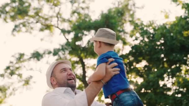 O pai está a circular nos braços do seu filho feliz no parque. Pai e criança brincando na floresta, rindo e abraçando juntos. Feliz viagem em família. O bebé está nos braços dos pais. Dia de folga dos pais. Família feliz — Vídeo de Stock