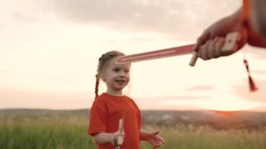Çocuk ve babası oyuncak kılıçla kavga ediyorlar. Kızları ve babaları ellerinde oyuncak kılıçlarla sahada ortaçağ şövalyelerini oynuyorlar. Bebek ve baba şövalyelik oynuyorlar. Mutlu çocukluk, aile