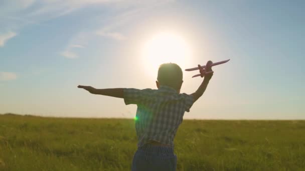 Il ragazzo corre con un aeroplano giocattolo. Figlio sogna di volare. Bambino felice, ragazzo, corre sul sole giocando con un aeroplano giocattolo sul campo estivo. La famiglia felice sta giocando nel parco. Bambino spensierato che gioca all'aperto — Video Stock