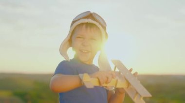Çocuk oyuncak uçağı elinde tutuyor. Oğlu uçmayı hayal ediyor, küçük pilot çocuk. Mutlu çocuk, çocuk, gökyüzünün önünde oyuncak uçakla oynuyor. Mutlu aile parkta oynuyor. Tasasız çocuk dışarıda oynuyor.
