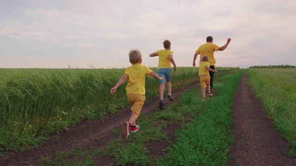 Familienbetrieb von Vater und Söhnen im Park. Glückliches Familienteam, das gemeinsam auf dem Feld herumtollt und freudig mit den Händen winkt. Söhne, Kinder, Papa rennen, spielen, freuen sich, genießen die Natur im Sommer. Teamarbeit in der Familie — Stockfoto