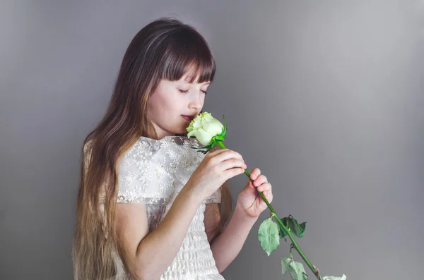 Menina cheirando uma bela rosa branca — Fotografia de Stock