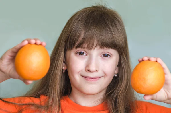 Girl holds orange oranges and smiling