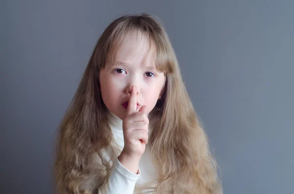 En pige holder en finger til munden - Stock-foto