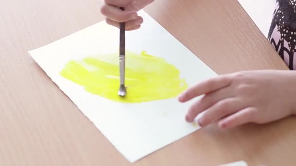 The child draws on a clean sheet yellow paint — Stock Video