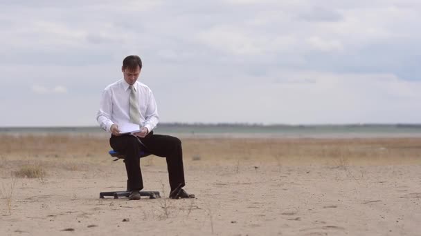 El hombre de negocios en el desierto en una silla — Vídeos de Stock