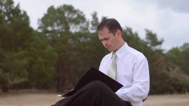 The person looks through documents in the black folder — Stock Video