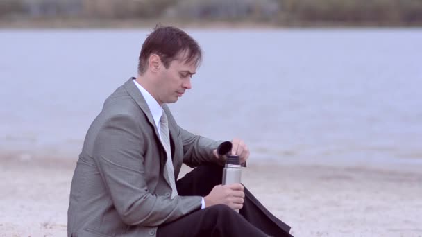 Мужчина сидит на берегу — стоковое видео