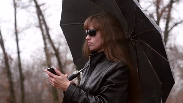 A mulher com telefone em uma capa impermeável — Vídeo de Stock