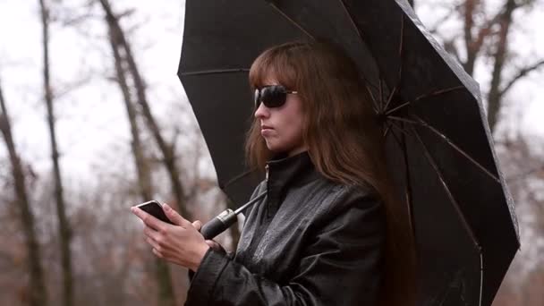 La mujer con el teléfono en el impermeable — Vídeo de stock