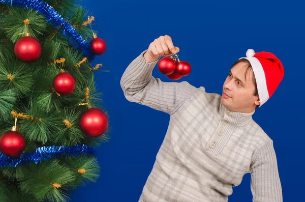 The man near an elegant New Year tree looks at toys. Stock Picture