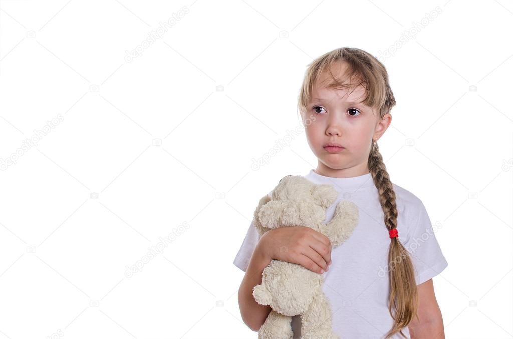 The sad girl holds a bear in hand