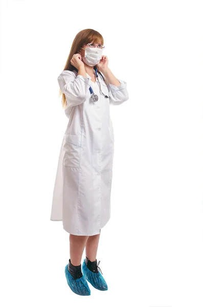 O doutor em uma máscara médica, um vestido de vestir branco e cov de bota — Fotografia de Stock