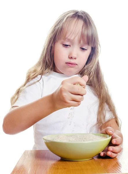 The girl pours from a hand to a plate rice — Stock Photo, Image