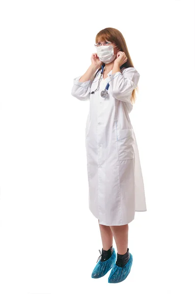 O doutor em uma máscara médica, um vestido de vestir branco e cov de bota — Fotografia de Stock