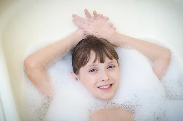 A menina está em uma casa de banho com espuma e sorrisos — Fotografia de Stock