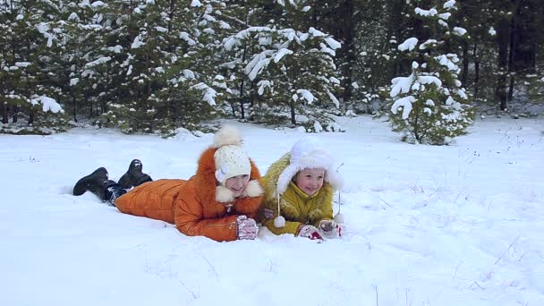 Zwei Mädchen liegen auf Schnee — Stockvideo