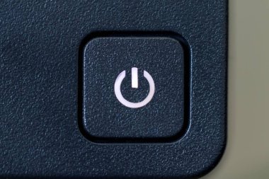 Bir bilgisayar ekranının açma kapama düğmesinin yakın plan portresi. Bilgisayar monitörü açık çünkü düğmenin sembolündeki ışık açık..